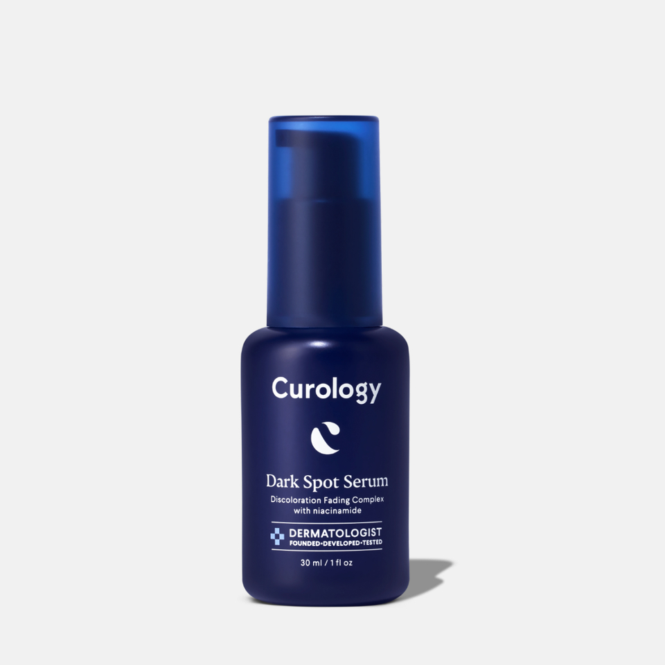 Curology Dark Spot Serum in a dark blue pump bottle, labeled ‘Discoloration Fading Complex with niacinamide,’ dermatologist founded, developed, and tested.