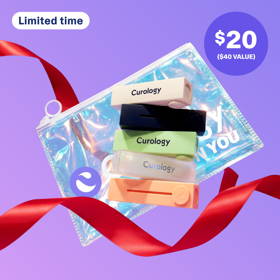 Five Curology Lip Balms in different colors stacked in front of a holiday-exclusive Holographic Gift Bag against a purple background with red ribbon trailing behind and underneath. The Lip Balms included are Original, Mint, Vanilla, Passion Fruit, and SPF 30.