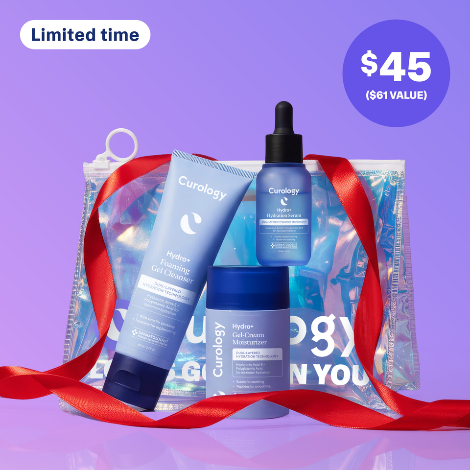 A set of three Curology products leaning against each other in front of a Holiday-exclusive Holographic Gift Bag against a purple background. The products included are the Hydro+ Foaming Gel Cleanser, Hydro+ Hydration Serum, and Hydro+ Gel-Cream Moisturizer.