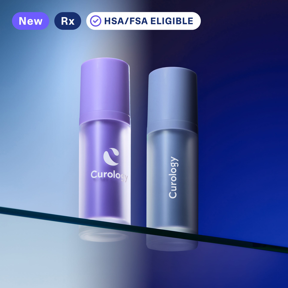 Purple and periwinkle cylindrical bottles of Curology DayPrime Rx and HydroTret Rx sit side by side on a glass shelf against a blue background. On the DayPrime Rx side, the blue background looks like daylight, and it looks like the night sky on the HydroTret Rx side.
